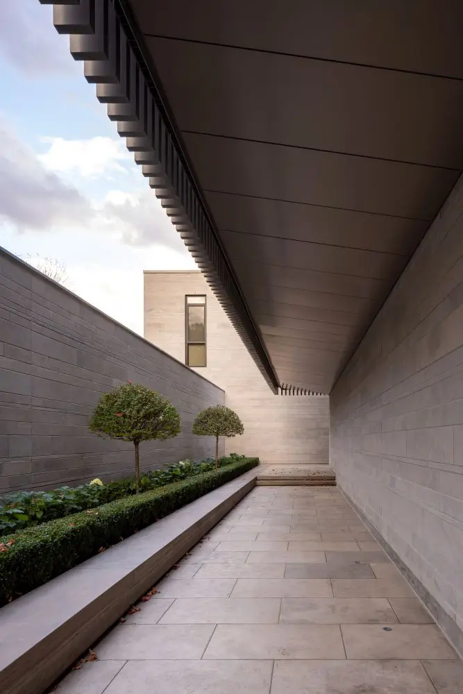 Covered stone walkway featuring clean lines and manicured greenery.