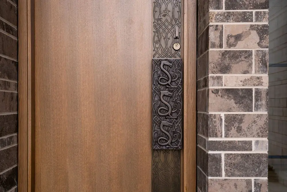 Custom wood front door with artistic metal inlay and brick surround.