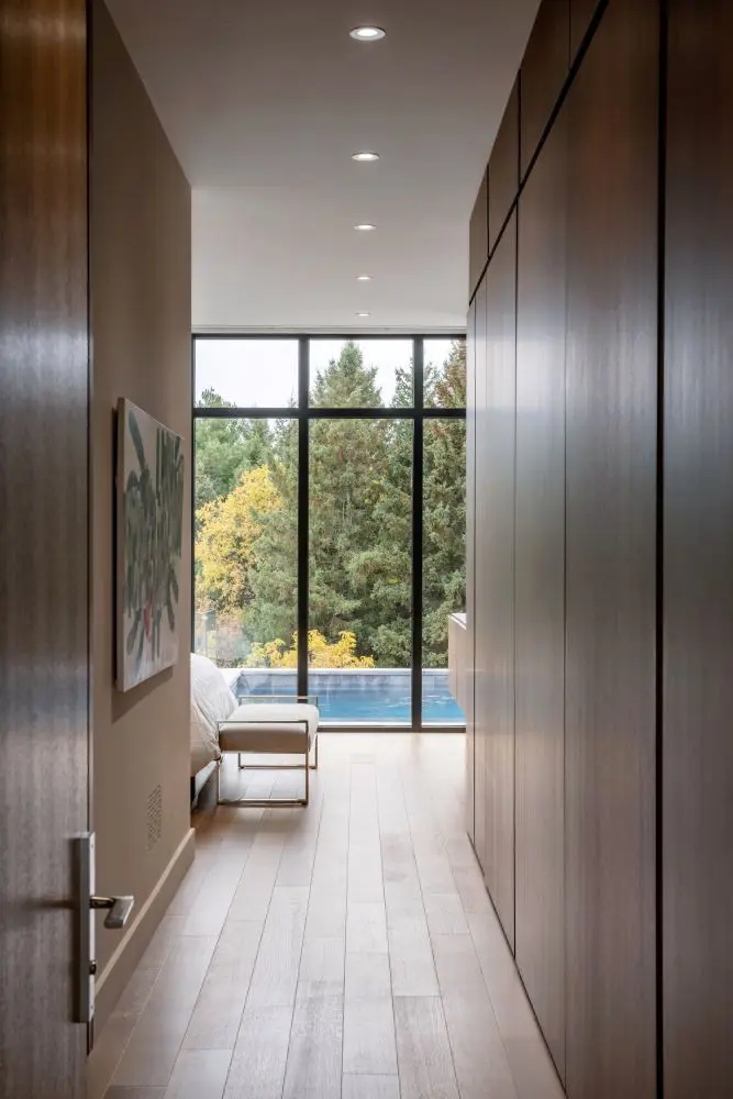 Hallway with wood paneling leading to seating area and pool view.