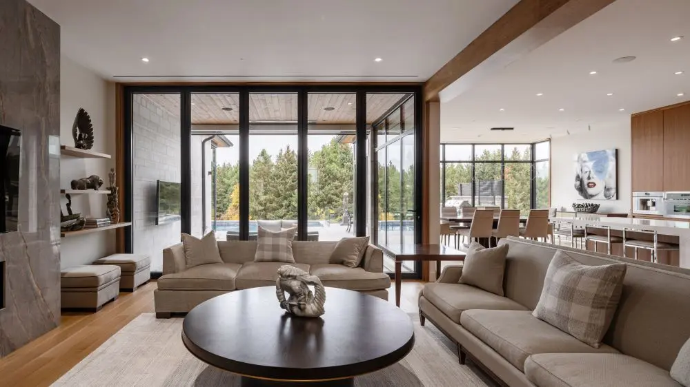 Open living space with neutral sofas, large windows, and seamless connection to dining and kitchen.