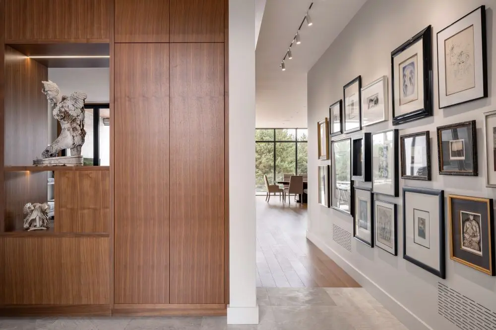 Hallway with art-lined walls leading to open-concept living and dining area.