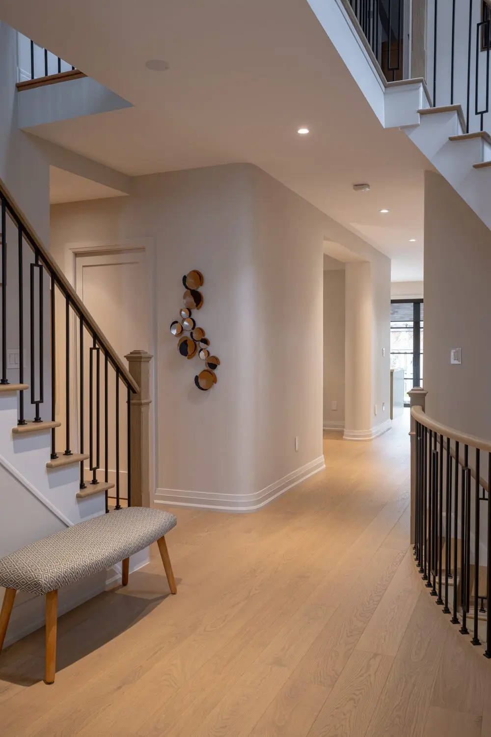 Entryway with wood staircase, metal railing, and bench seating.