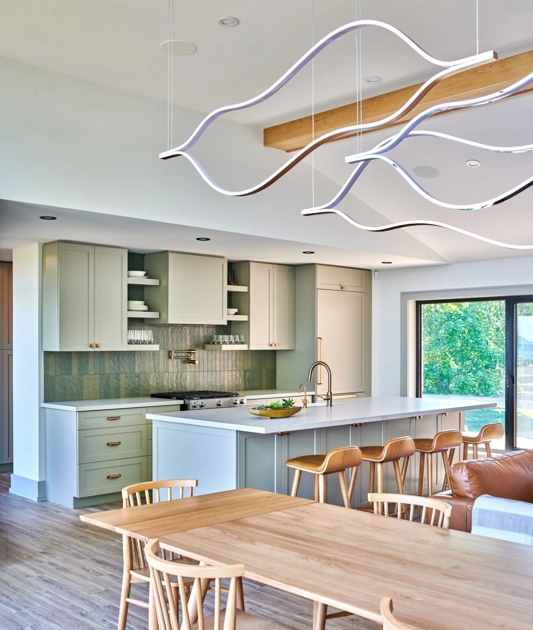 Dining area with sculptural light fixture beside open kitchen and large windows.
