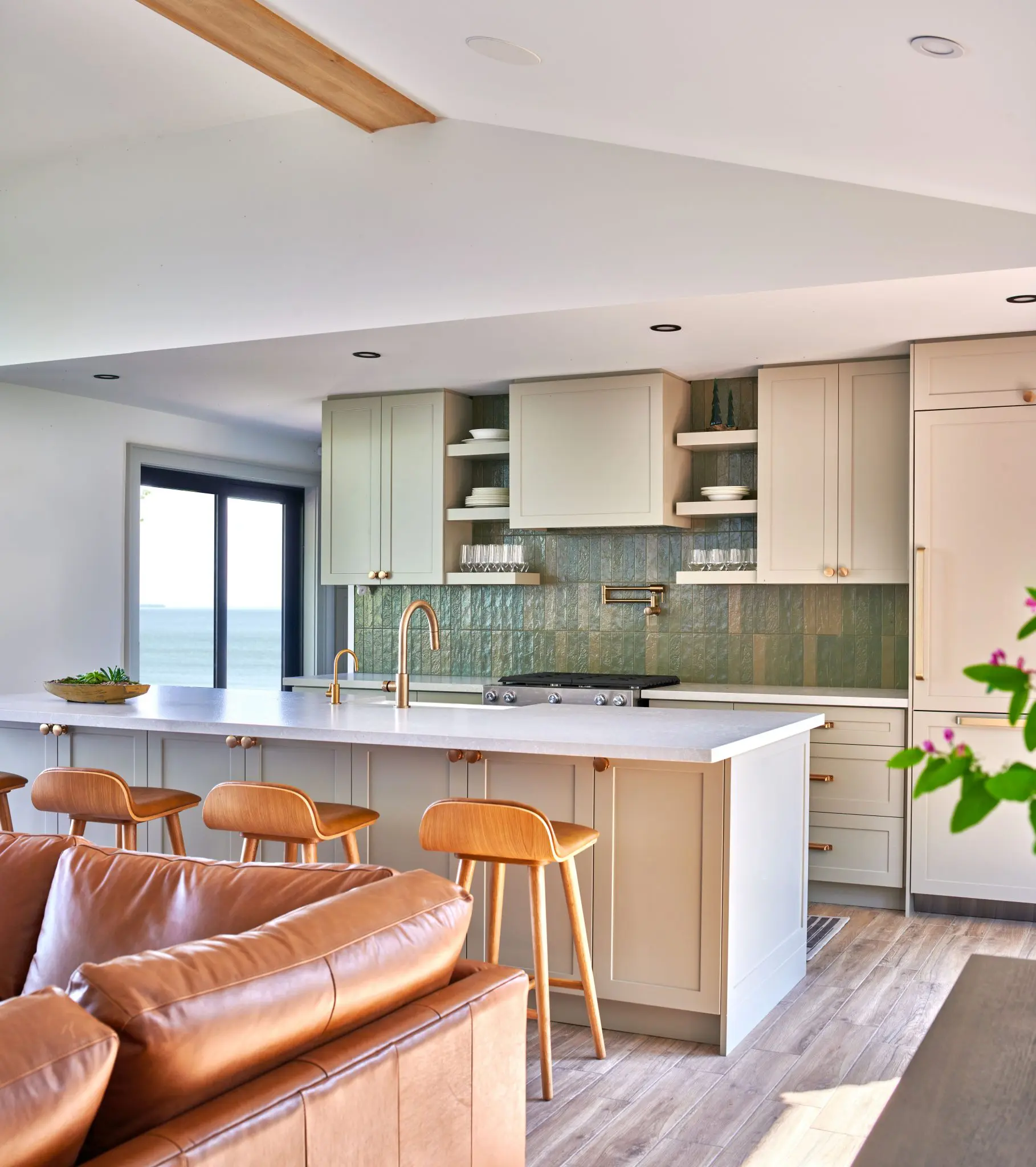 Modern kitchen with island seating, green tile backsplash, and lake view.