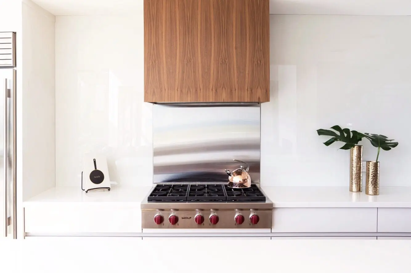 Modern kitchen range with wood cabinetry, stainless backsplash, and minimalist decor.