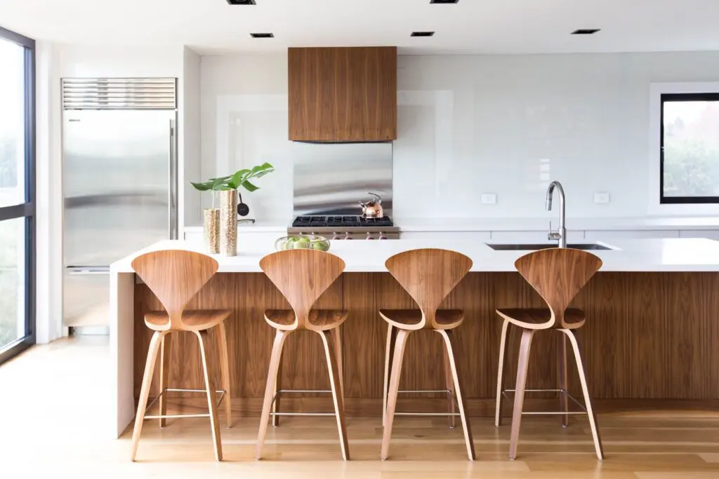 Sleek kitchen with walnut cabinetry, white countertops, and natural light.