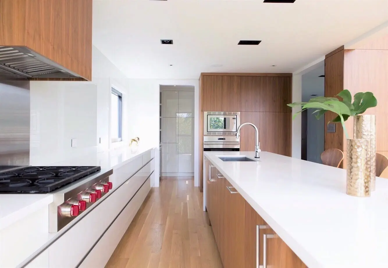 Bright contemporary kitchen with white countertops, wood cabinetry, and built-in appliances.
