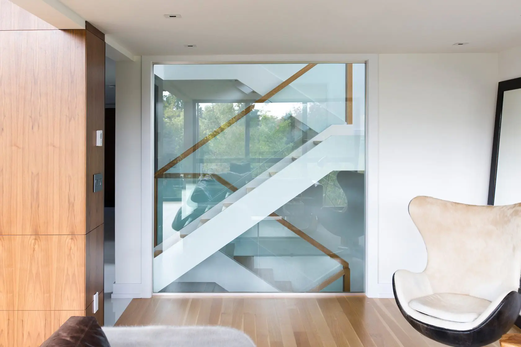 Staircase with glass railing connecting bright modern living areas.