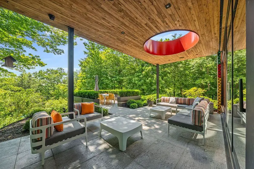 Outdoor lounge with red skylight feature and forest backdrop.
