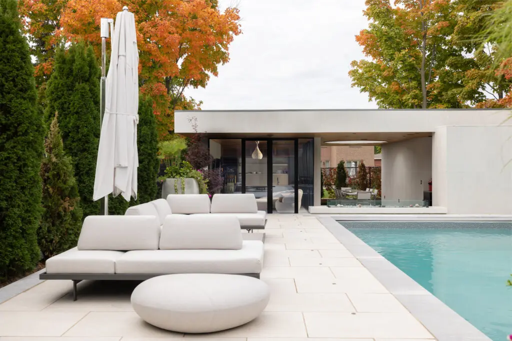 Contemporary poolside view of modern cabana with lounge seating, glazed façade, and dining pavilion.