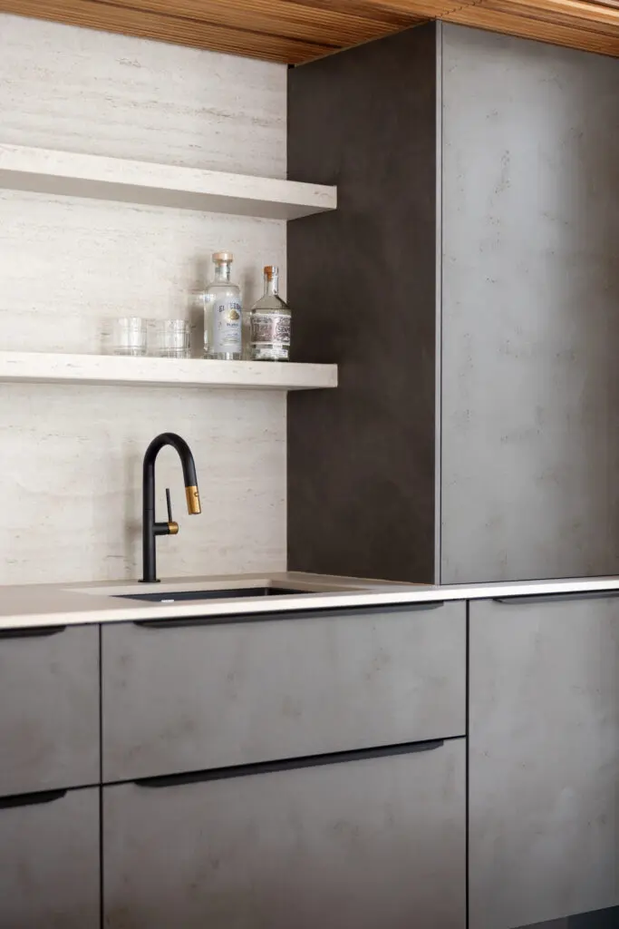 Detail of modern cabana bar with minimalist shelves, stone backsplash, and matte cabinetry.
