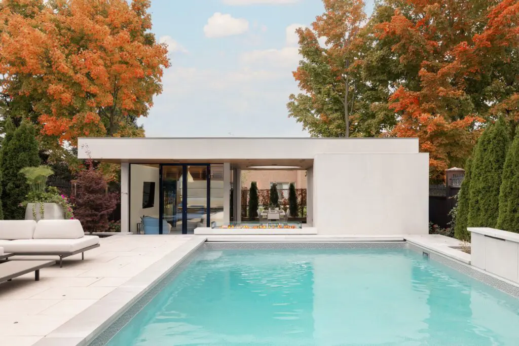 Contemporary poolside view of modern cabana with lounge seating, glazed façade, and dining pavilion.