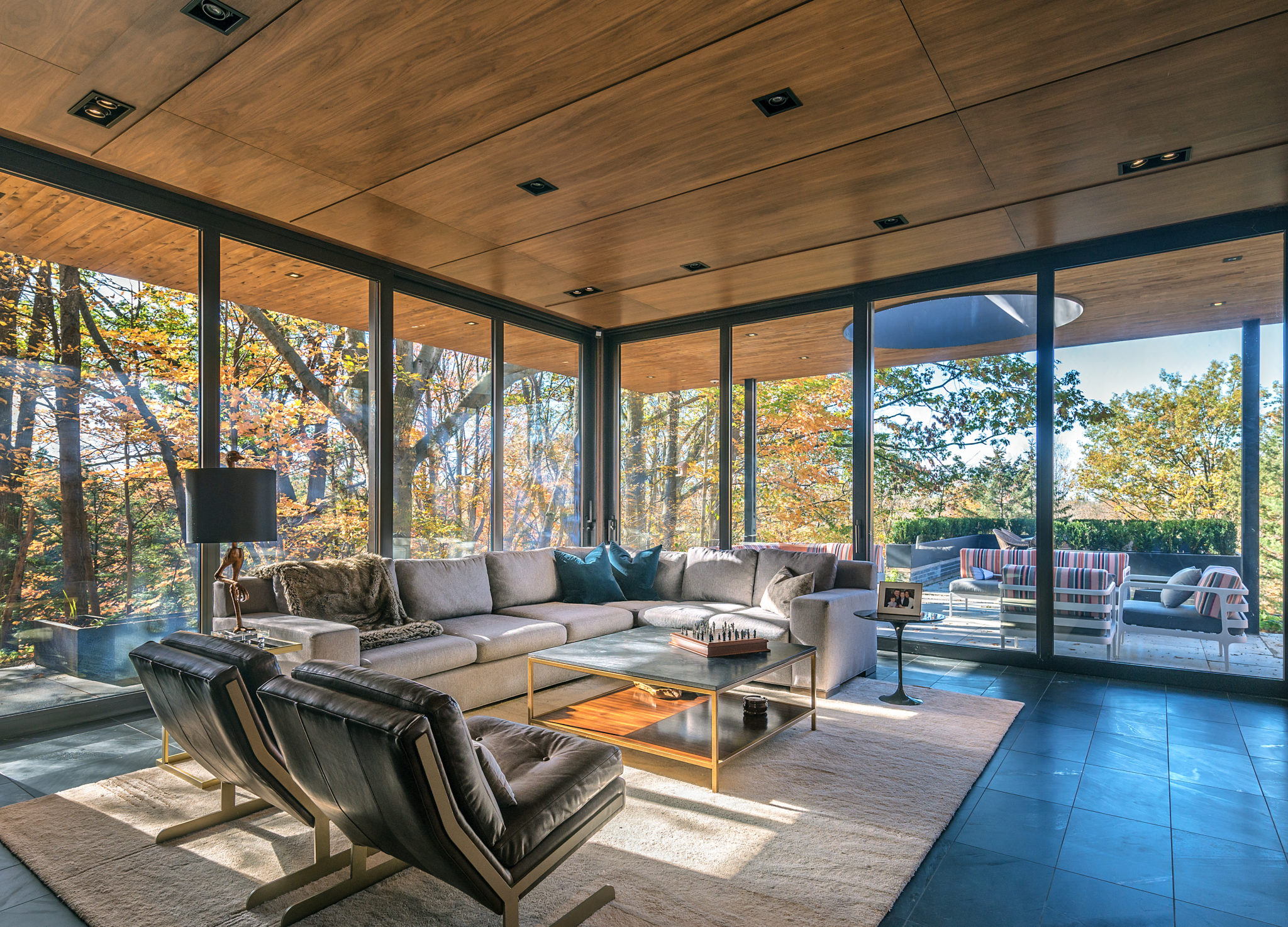 The interior of a beautifully bright indoor living space with floor to ceiling windows renovated by Frankfranco Architects on their Woodland Ridge custom home renovation project.