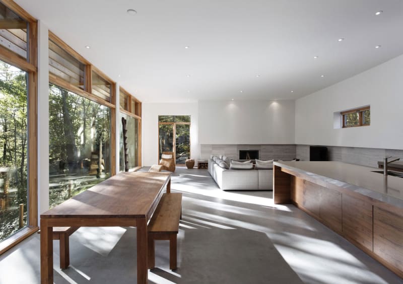 Interior of a modern cottage design featuring a large farm table. Carling Residence in Muskoka